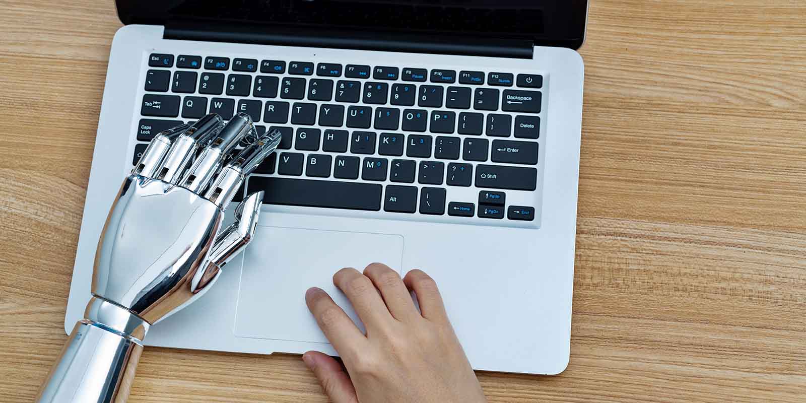 Robot and human arm using laptop, representing job seeker's use of AI and technology in job search