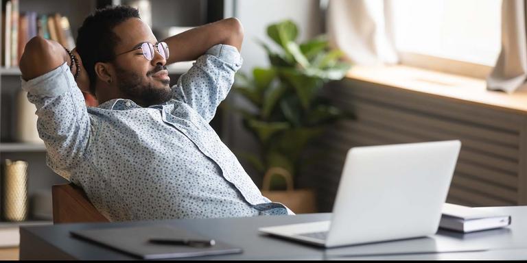 Relaxed professional working on a laptop at his desk, leaning back in his chair, working from home for a low-stress, high-paying job