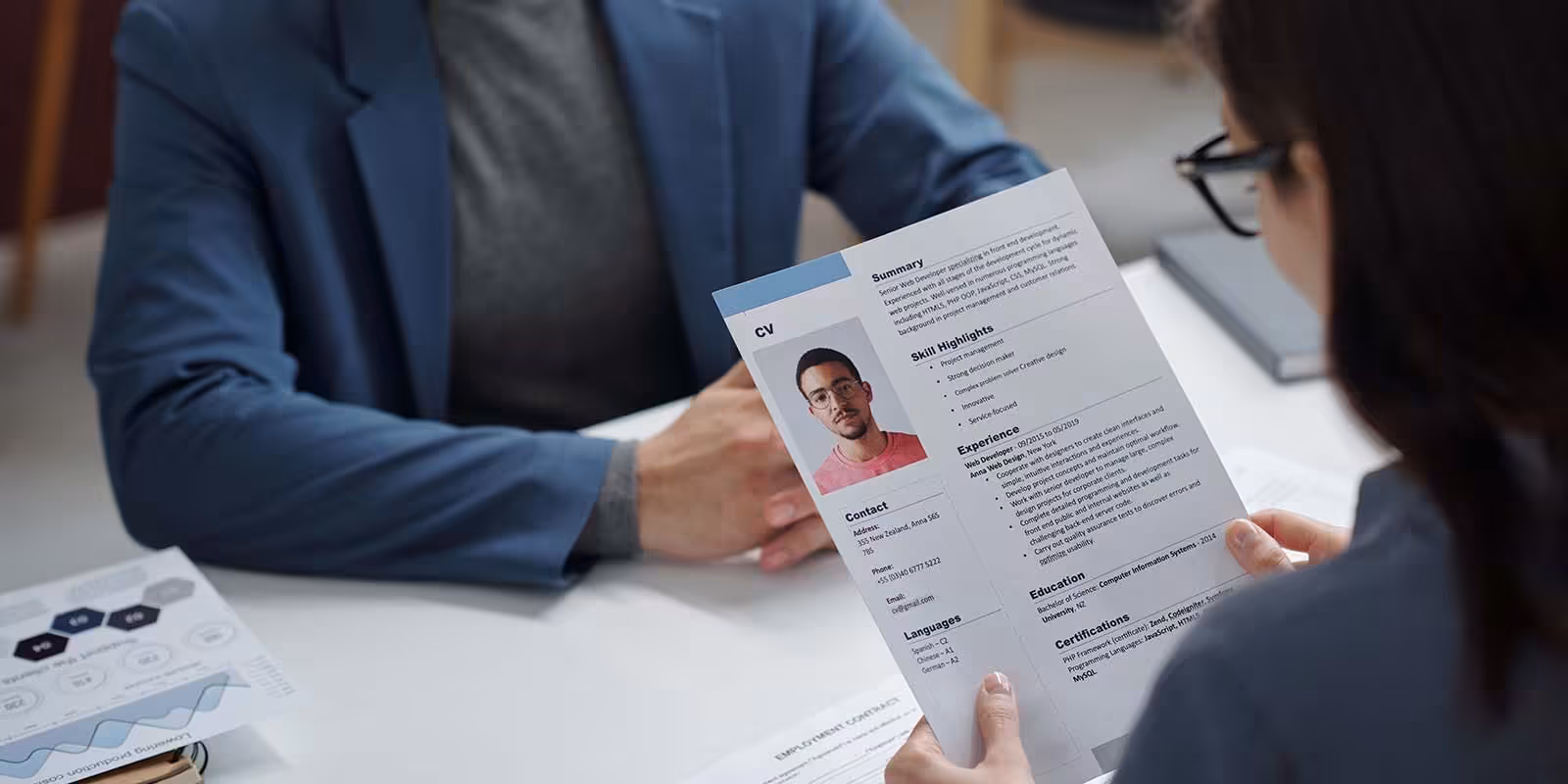 Interviewer reviewing a candidate’s CV, highlighting key skills and experience for a job application