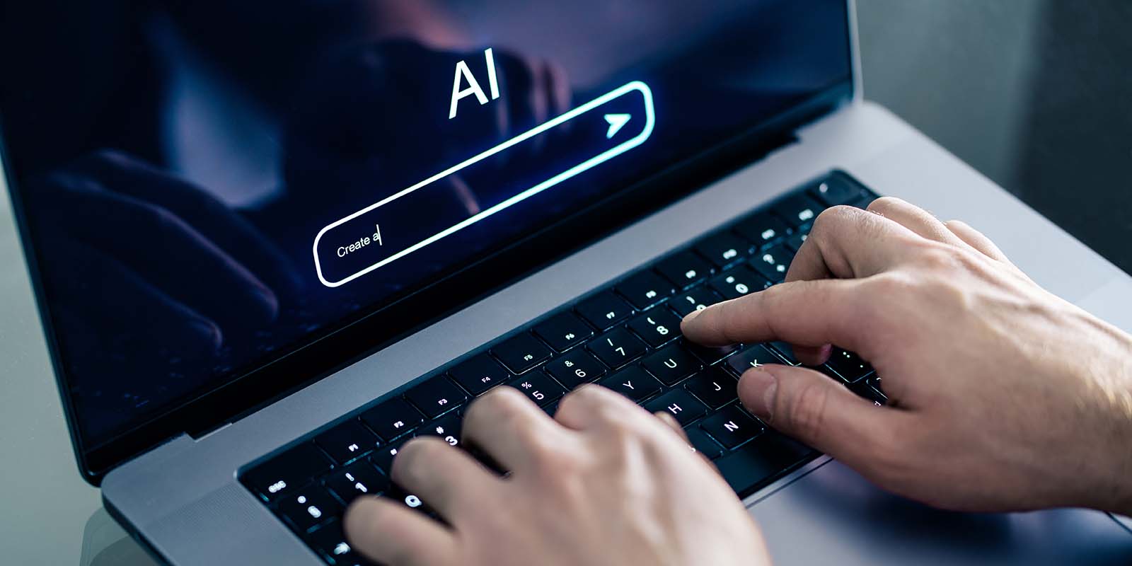 A close-up view of a person’s hands typing on a laptop keyboard. The laptop screen displays an AI interface with a search bar that contains the text "Create a|" and an "AI" logo above it.